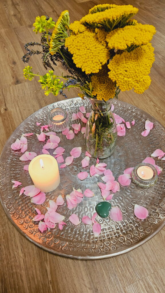 Dekoriertes Silbertablett mit Kerzen, gelben Blumen und Rosenblüten – Liebevolles Setting für einen Frauenkreis und Mother Blessing Ritual.